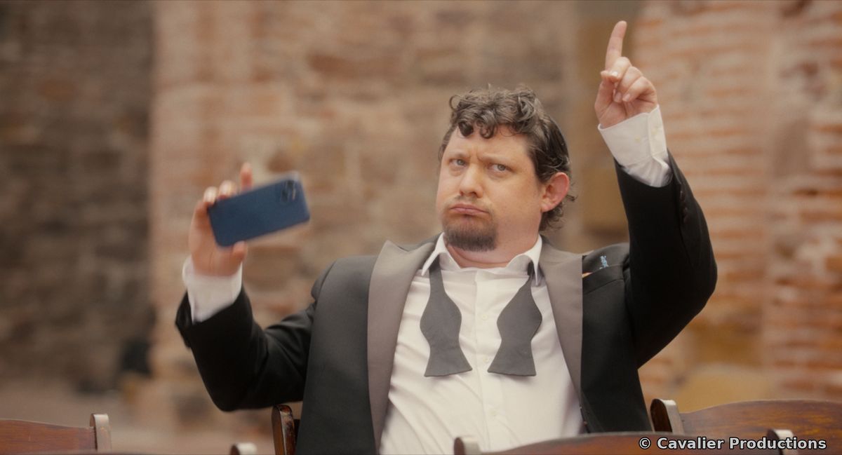 A wedding guest holding up his phone and pointing skyward